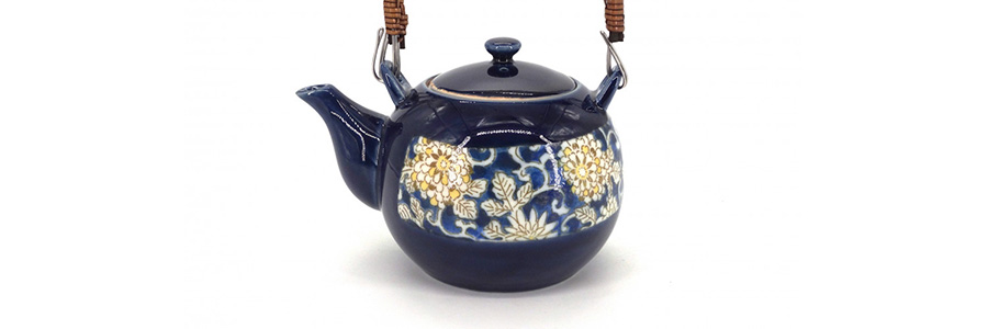 Une théière en céramique bleue avec des motifs de fleurs.